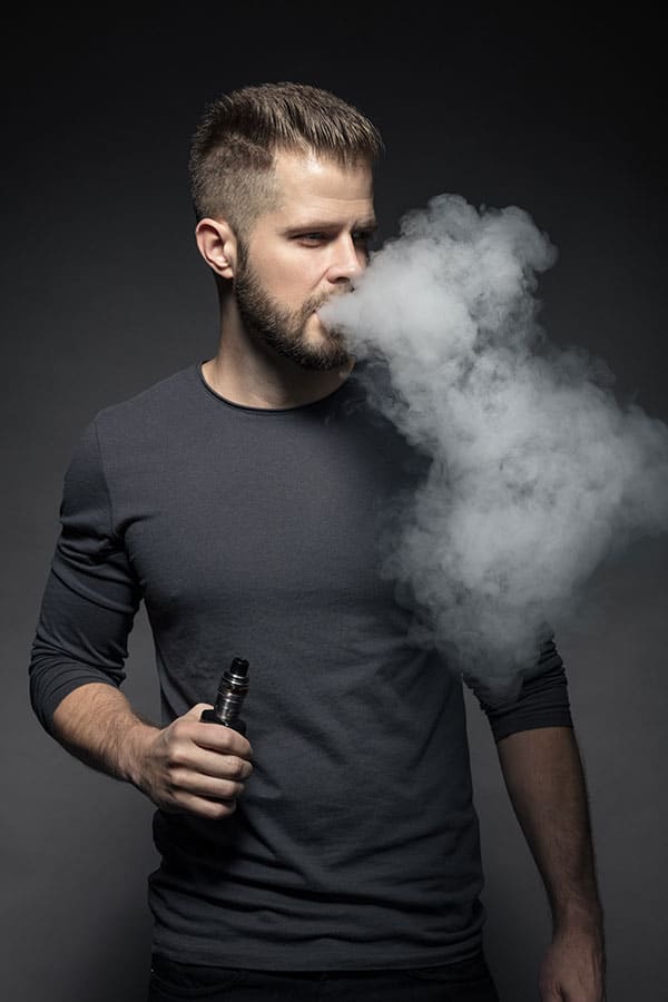 Compelling image of a man vaping, prominently featuring the Vapemilitia brand and highlighting the powerful 'Double Barrel' experience. This visual representation seamlessly aligns with the page's context, offering a glimpse into the robust and satisfying vaping culture curated by Vapemilitia.